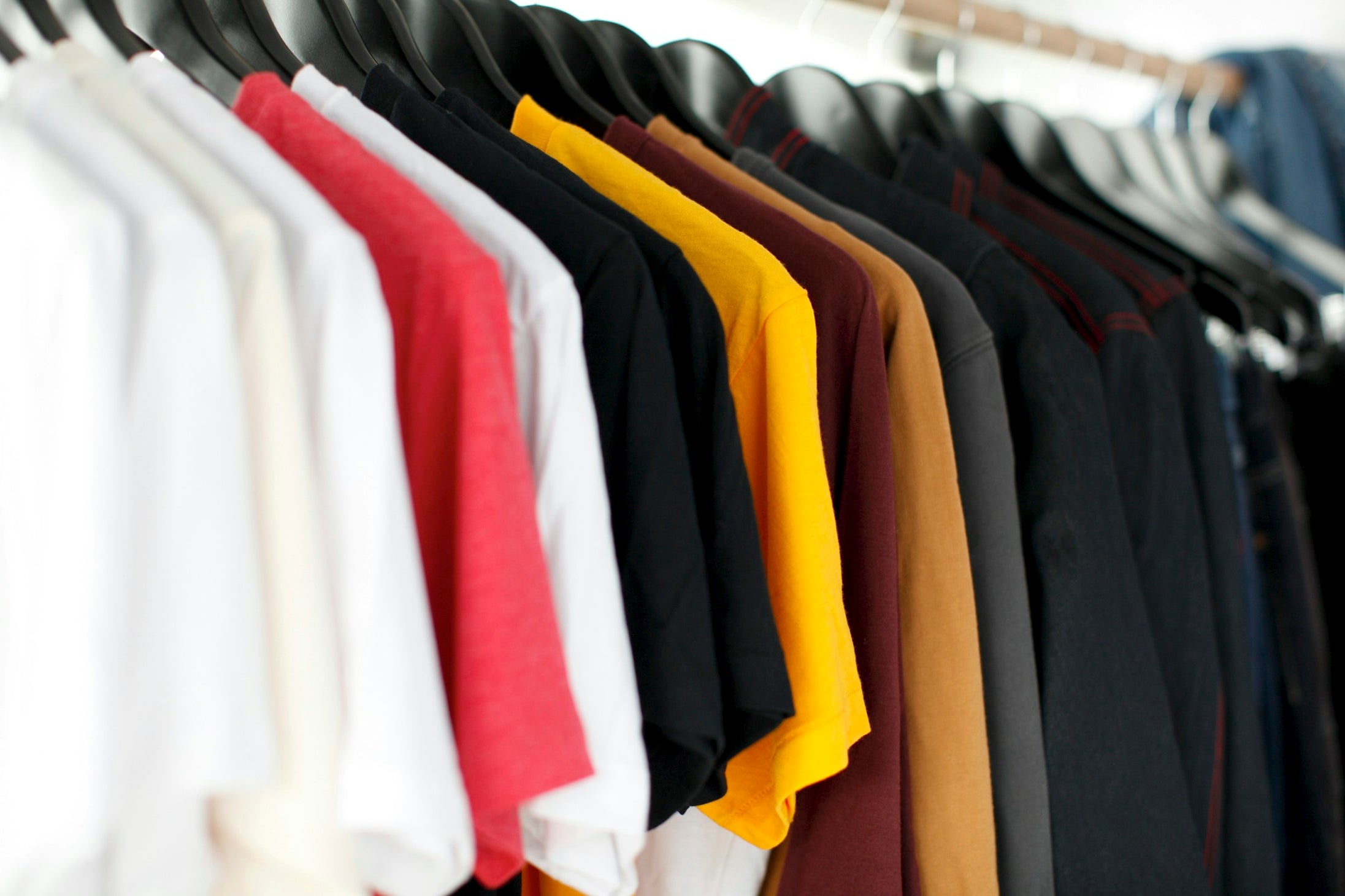 A close view of shirts hanging on a retail rack, representing the same product sold at different prices across wholesale and direct channels