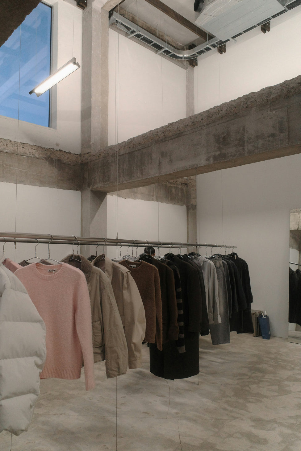 Autumn winter garments hanging on a rail in a minimalist boutique, ahead of peak trading season